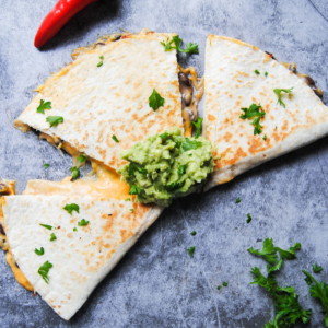 overhead view of a sweet potato quesadilla divided into 3 triangles with a dollop of guacamole