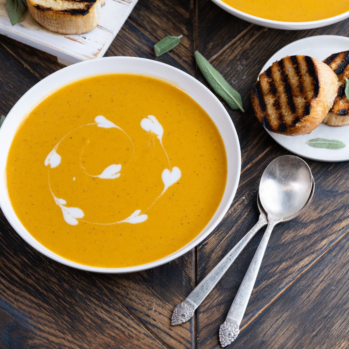 Bowl of sweet potato soup with two spoons and grilled bread