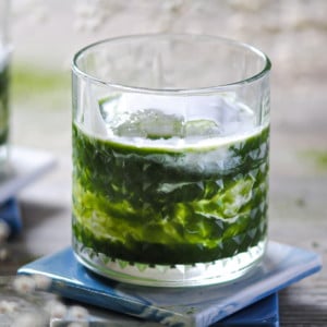 cocktail with matcha and cream swirls in a whiskey tumbler glass