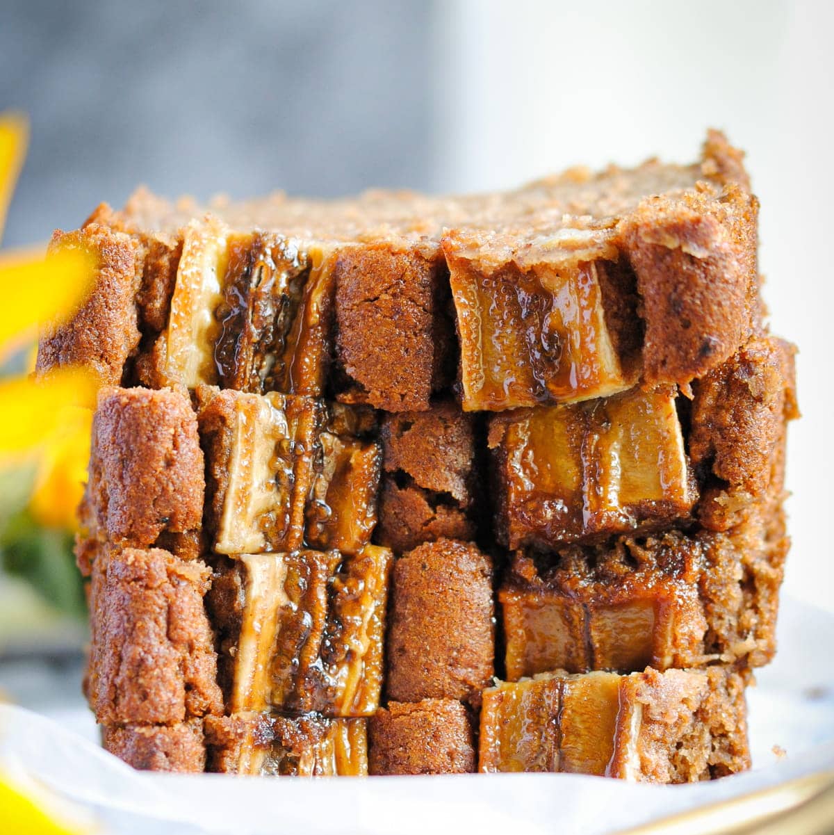 Slices of Vegan Blender Banana Bread stacked on top of each other with a sunflower
