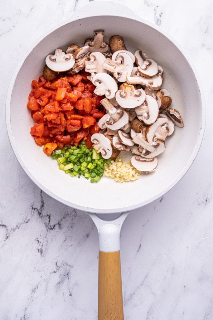 Sautéing vegetables in a white pan with olive oil