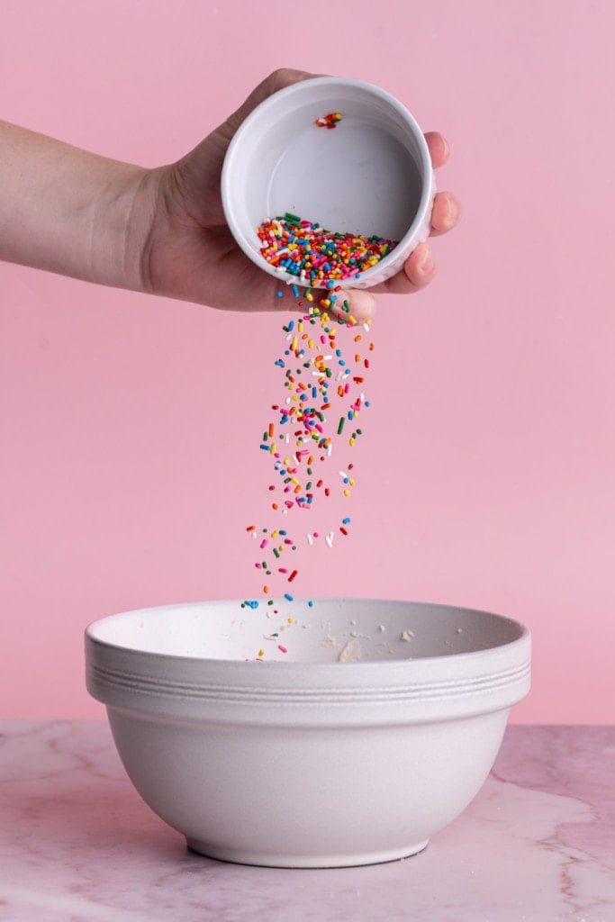 Adding rainbow sprinkles to edible cookie dough