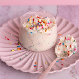 Edible Funfetti Cookie Dough in a glass cup resting on a pink plate