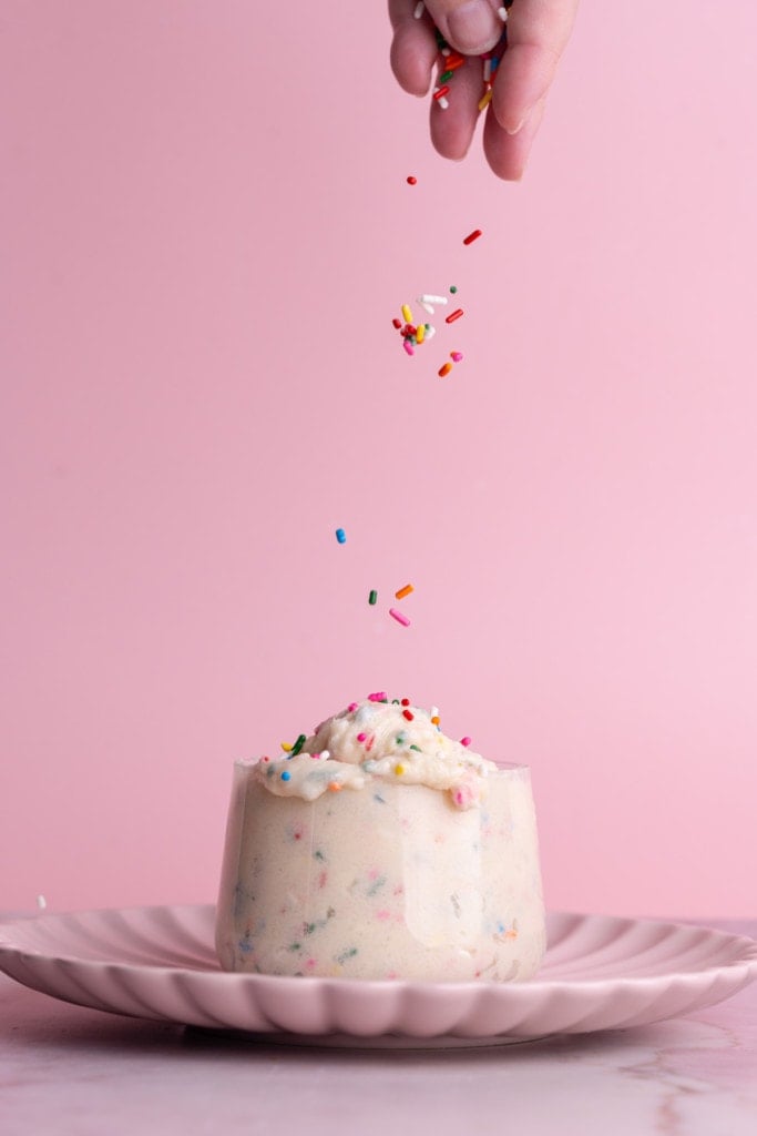 Adding extra sprinkles to cup of edible Funfetti cookie dough