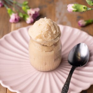 No-bake sugar cookie dough in a jar with pink flowers in the background.