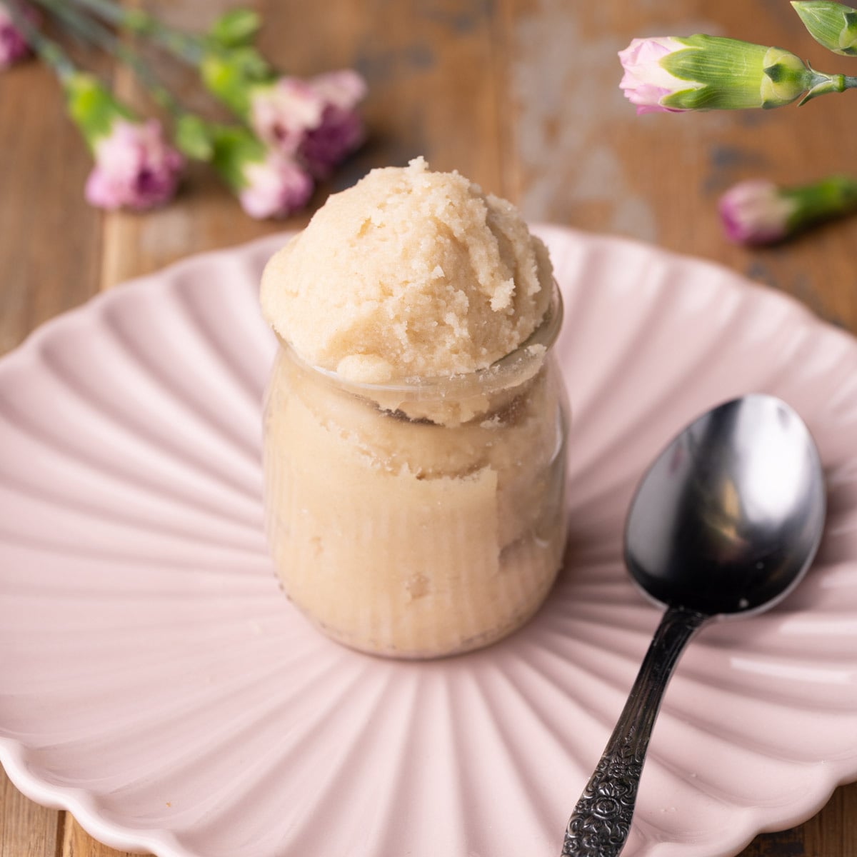 Edible Sugar Cookie Dough New Featured Image No-bake sugar cookie dough in a jar with pink flowers in the background.