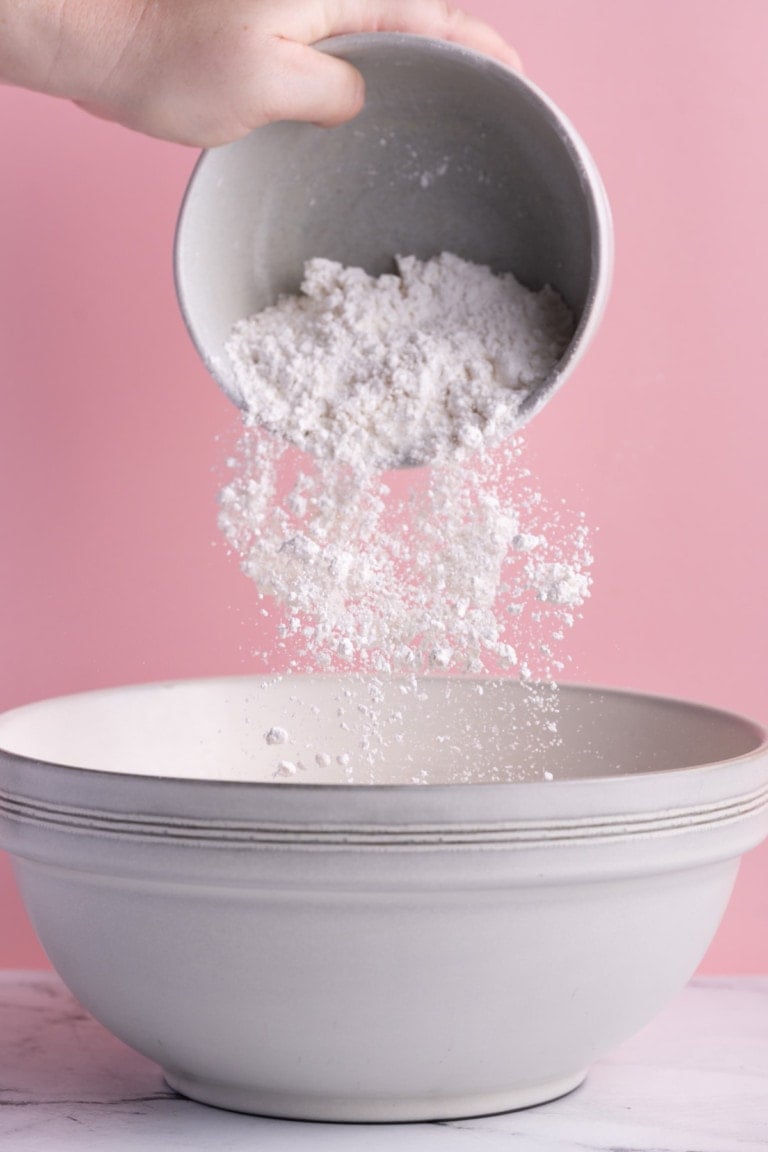 Adding dry ingredients of pancake batter to large mixing bowl