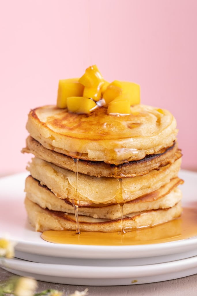 Close up of mango pancakes with syrup dripping down off the sides of the stack