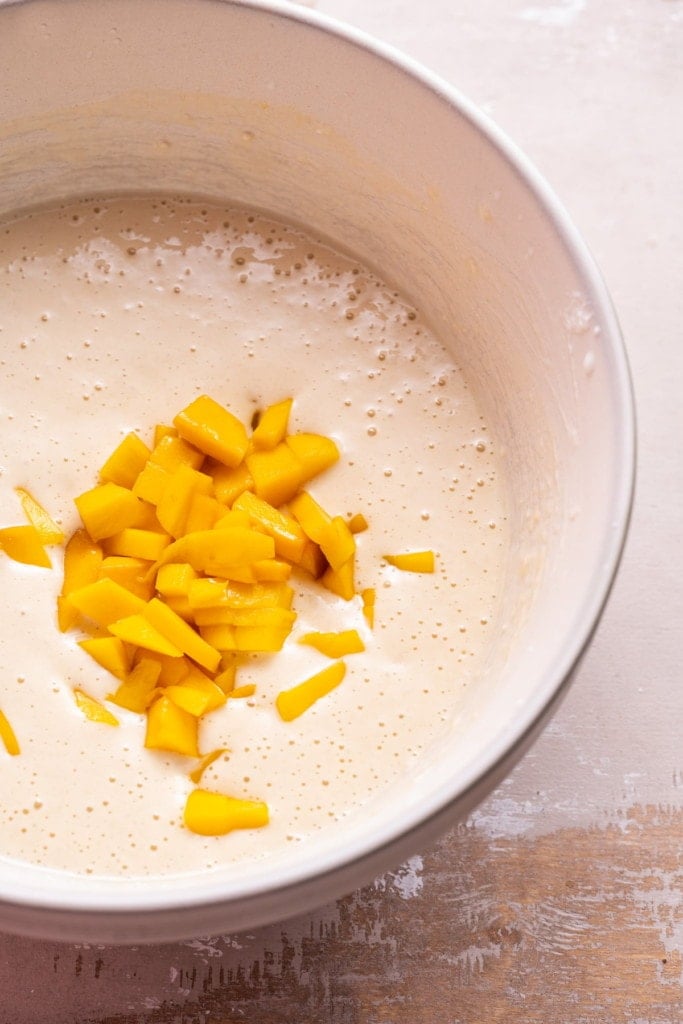 Folding in diced mango into pancake batter