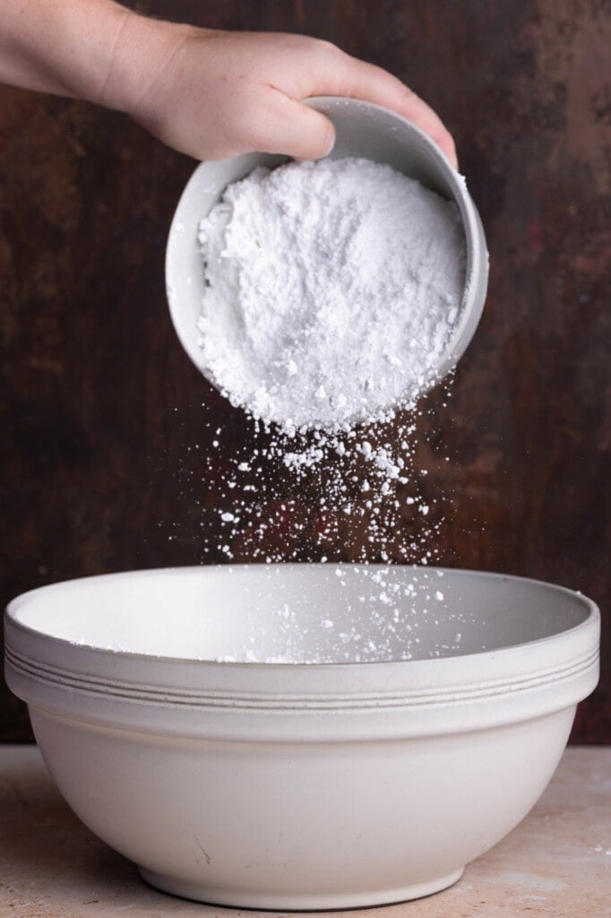 Adding powdered sugar to a large mixing bowl