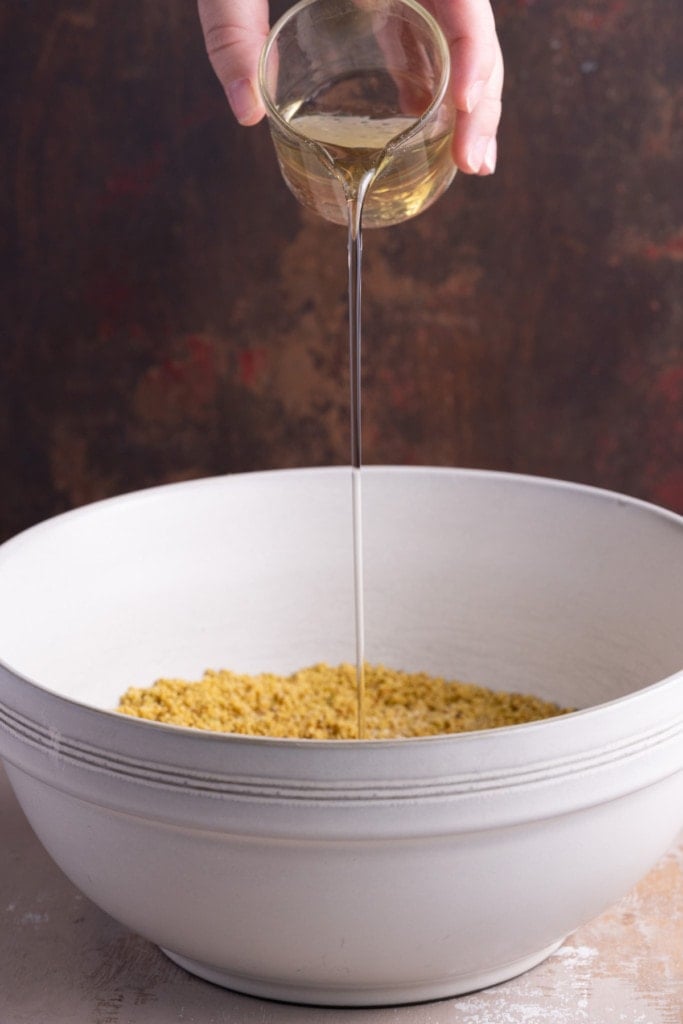 Adding oil to pistachio and sugar mixture to make muffins