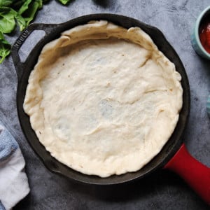 quick pizza dough spread in a cast iron skillet