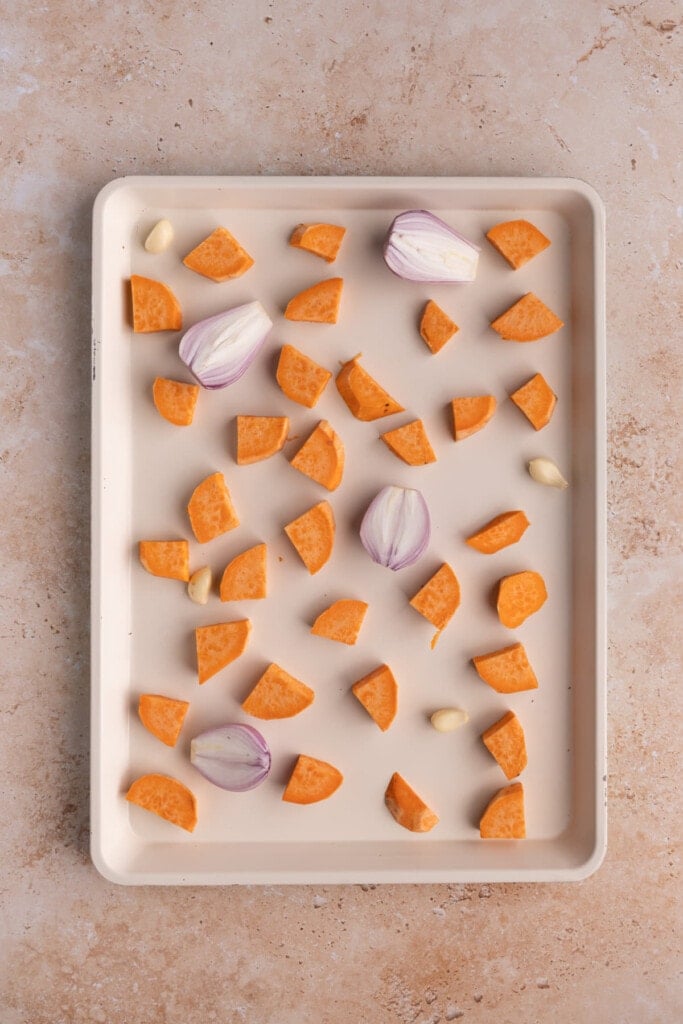 Baking sheet with sweet potato, shallot, and garlic