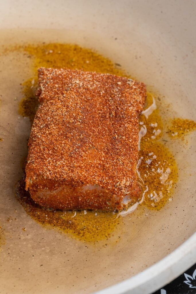 Blackened Cod cooking on one side in a hot pan with oil.
