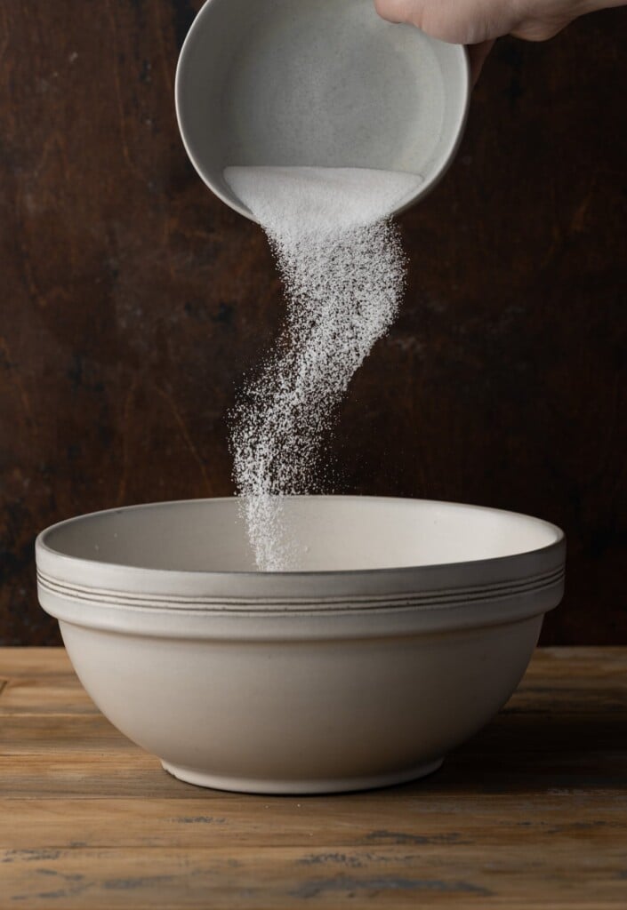 Adding sugar to bread pudding mixture.