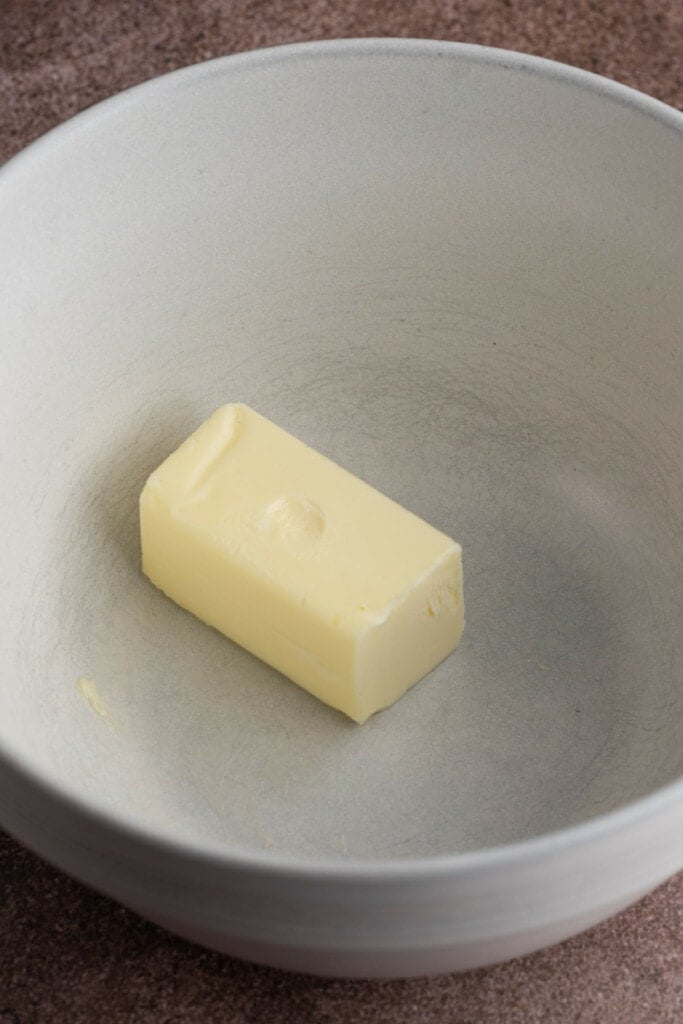 Poking butter with finger to see if it leaves an imprint to test if its softened