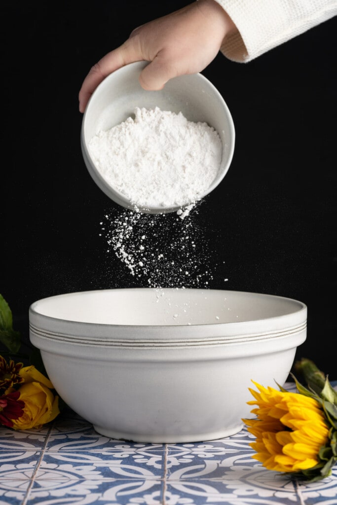 Adding flour to a large mixing bowl to make pancake batter without milk