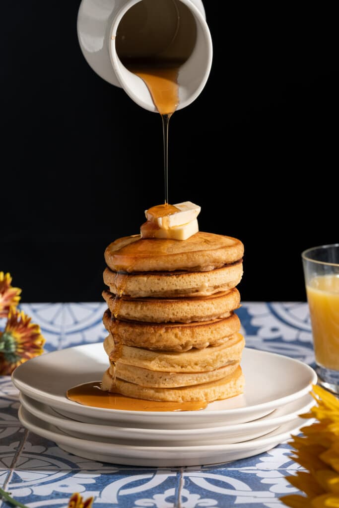 Pouring syrup on a stack of pancakes