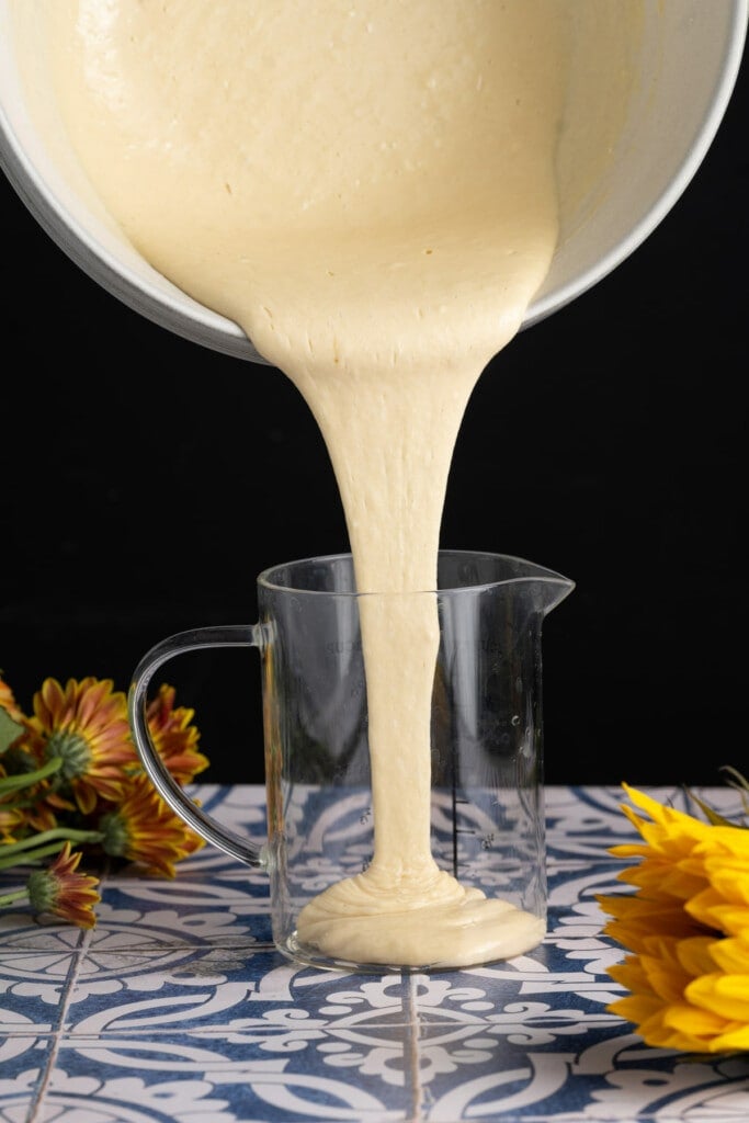 Pouring pancake batter into a measuring cup to more easily form them in the pan