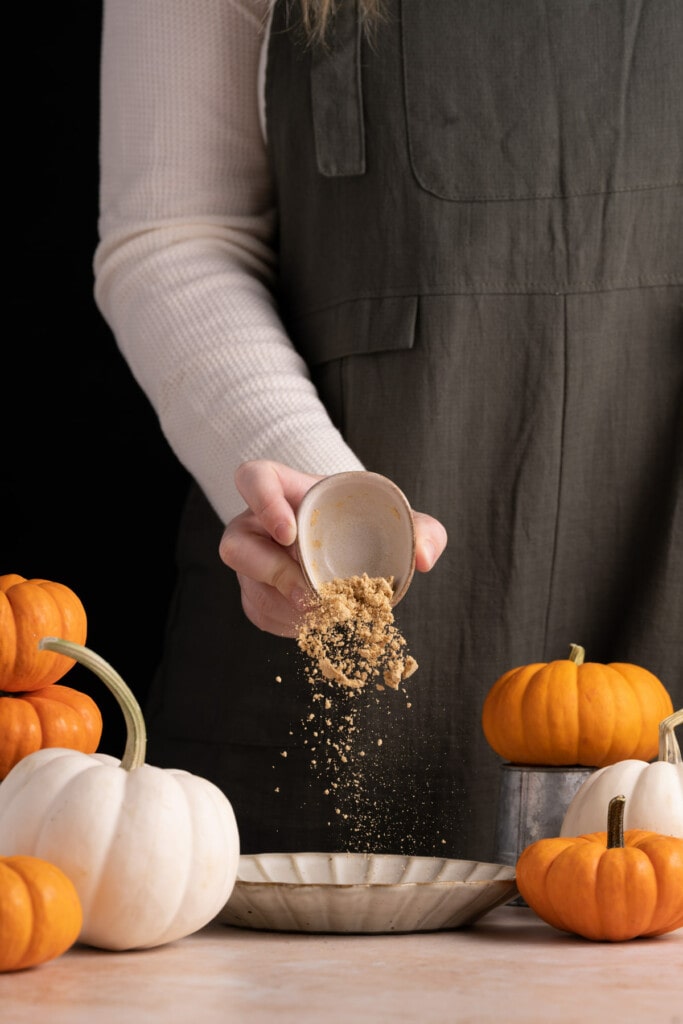 Pouring ground ginger into a bowl to make Pumpkin Pie Spice