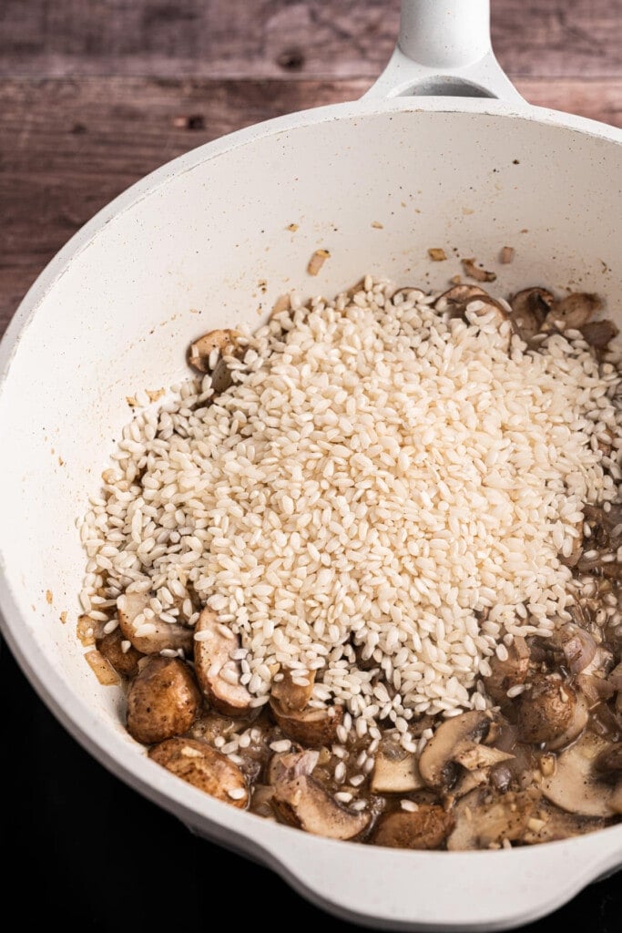 Adding Arborio rice to cooked shallots, mushrooms, and garlic
