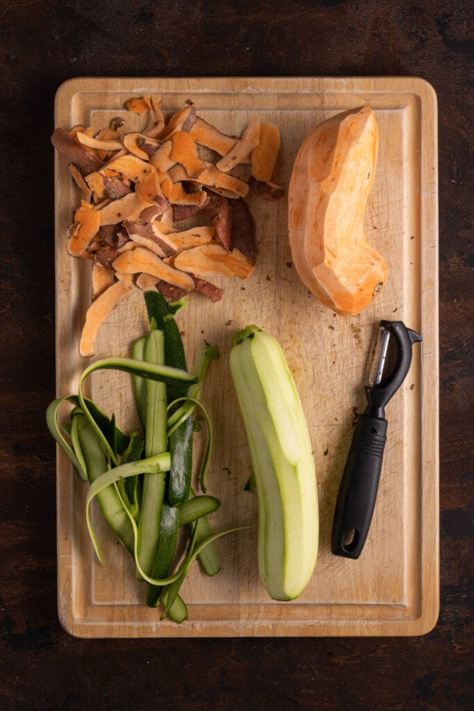 Zucchini and sweet potato peeled on a chopping board