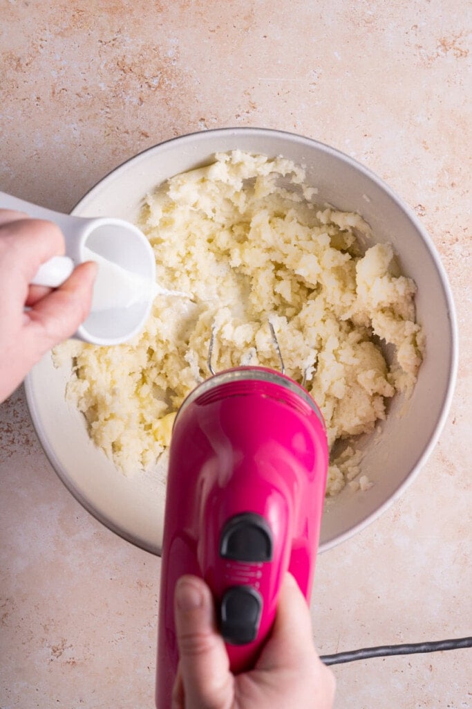 Adding extra moisture to mashed potatoes with hand mixer on