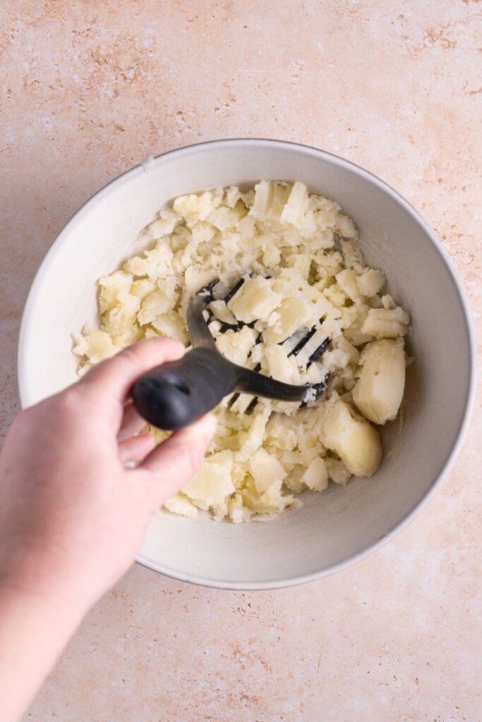 Using potato masher to make sure there are no lumps in Truffle Mashed Potatoes