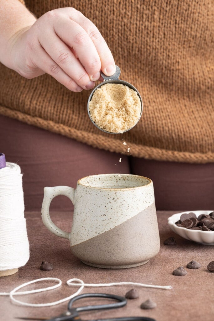 Adding light brown sugar to mug 