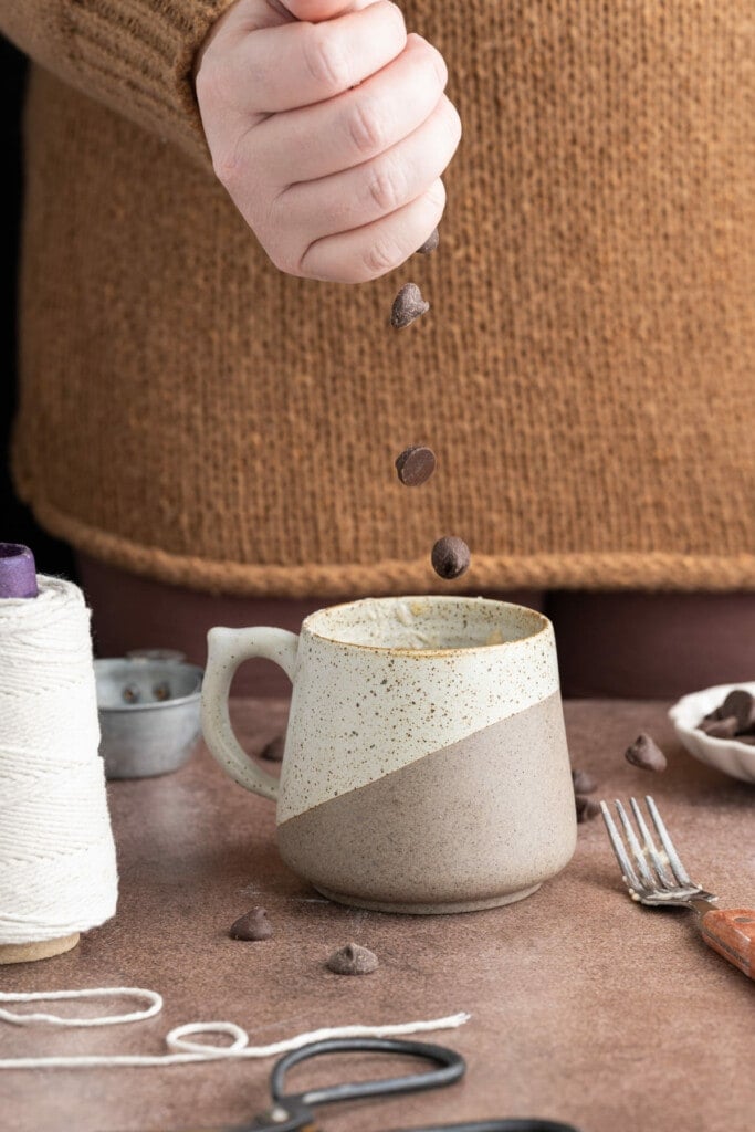 Adding chocolate chips to mug cake