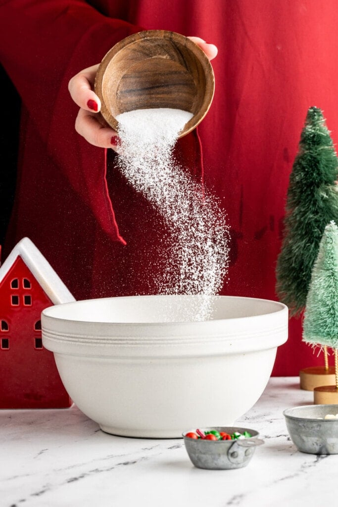 Adding granulated sugar to mixing bowl to make hot cocoa