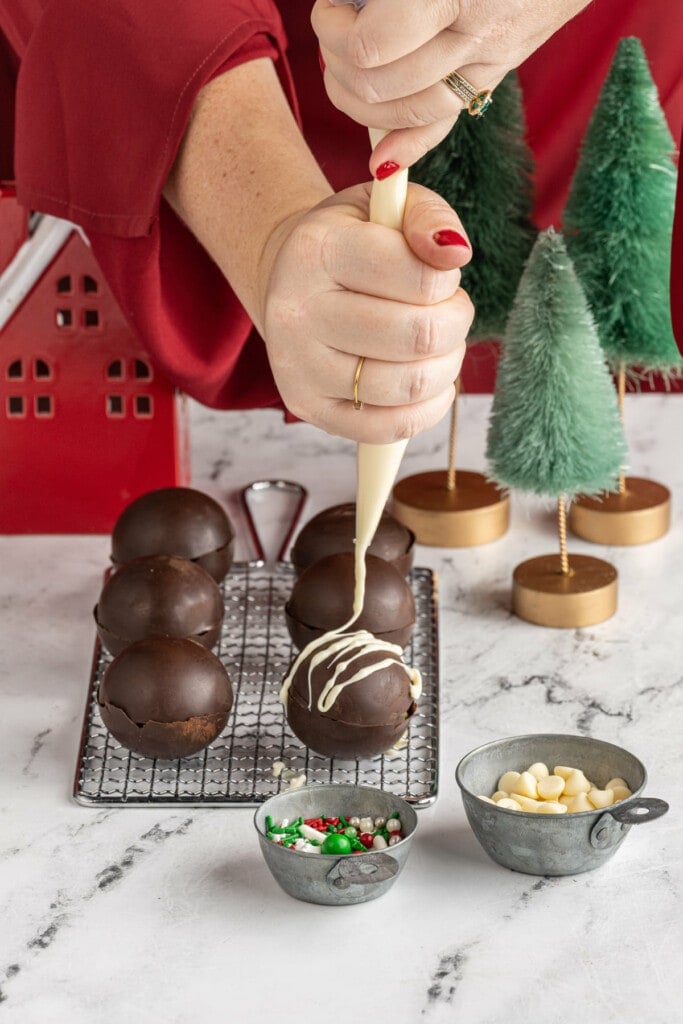 Drizzling white chocolate on hot cocoa bombs