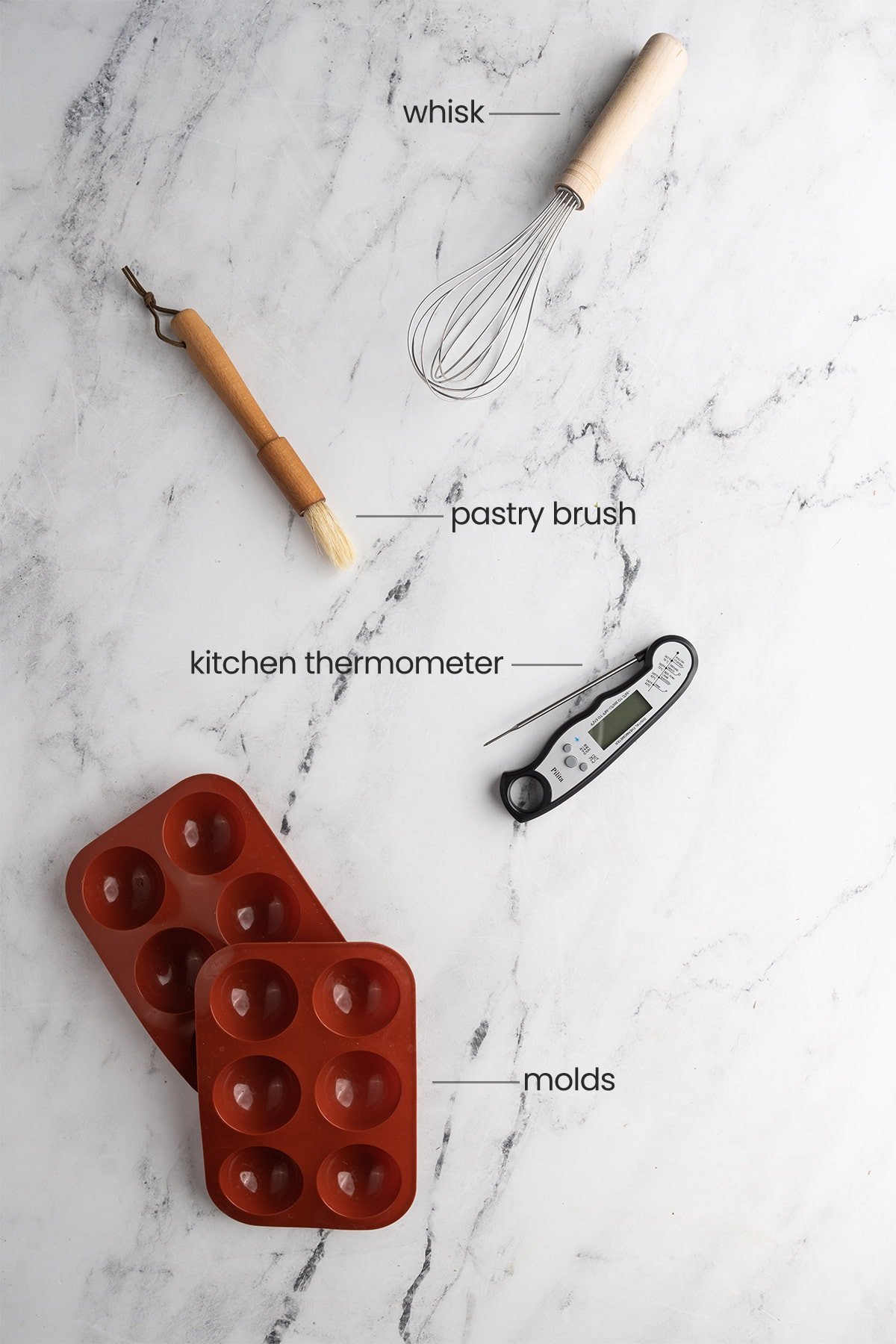 equipment needed to make hot chocolate bombs - whisk, pastry brush, kitchen thermometer, molds