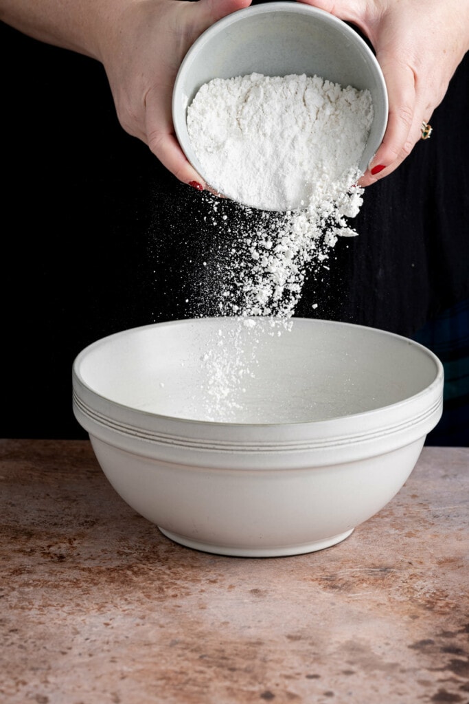 Adding flour to a mixing bowl to make dairy-free waffle batter