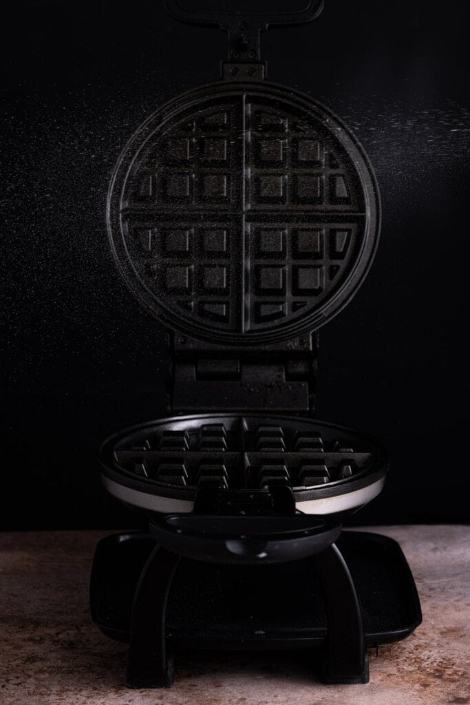 Spraying waffle iron with oil