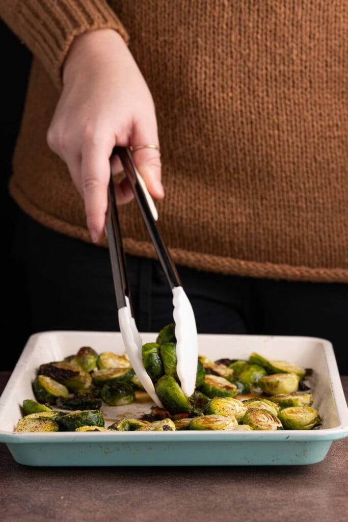 Tossing hot brussels sprouts in maple syrup and balsamic vinegar