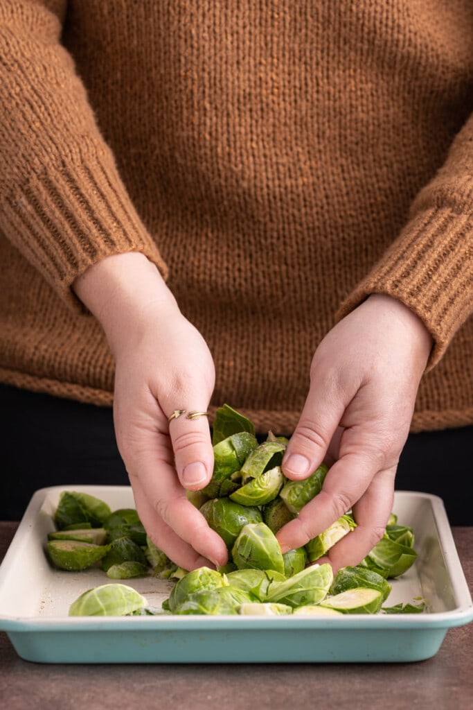 Tossing brussels sprouts in oil and seasoning to prepare for roasting