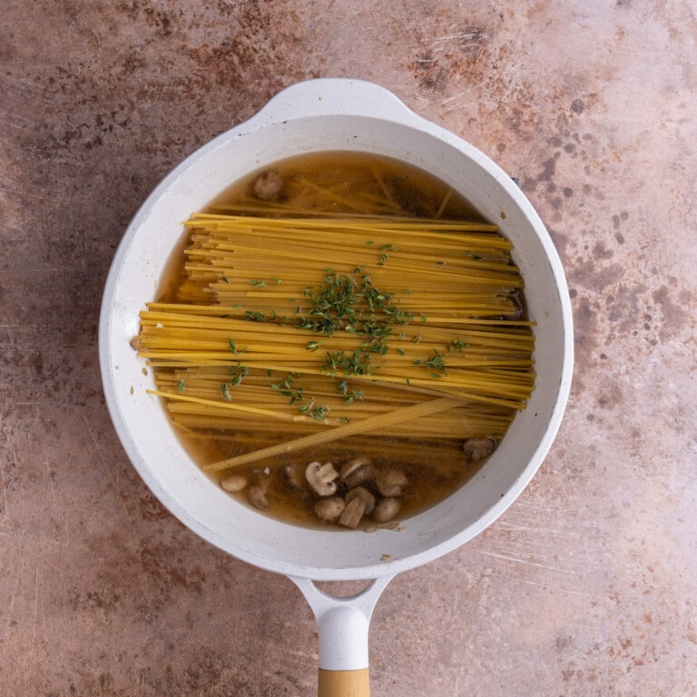 Pasta submerged in vegetable broth and Marsala cooking wine in a saucepan