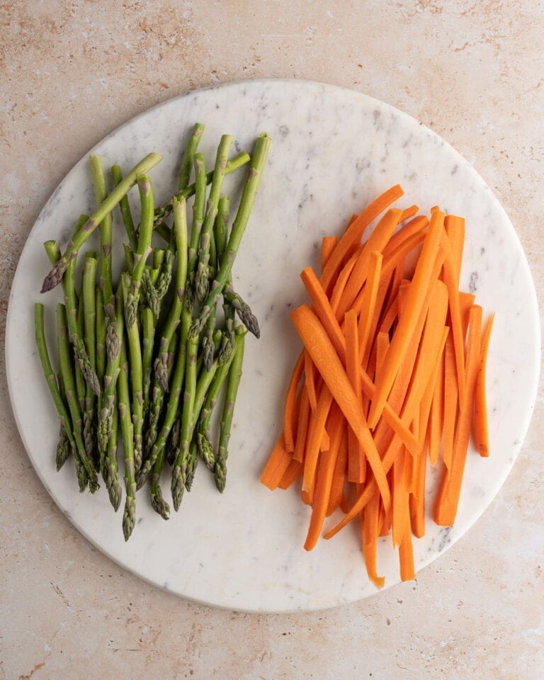 prepped sliced carrots and asparagus on a round slate