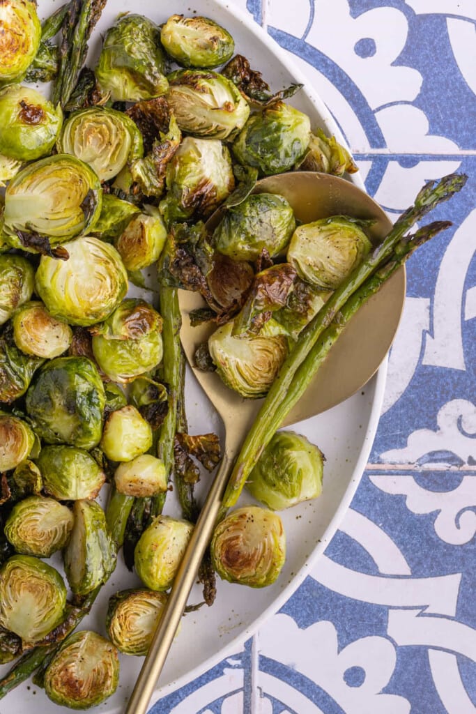 Close up of asparagus and brussels sprouts on platter with serving spoon