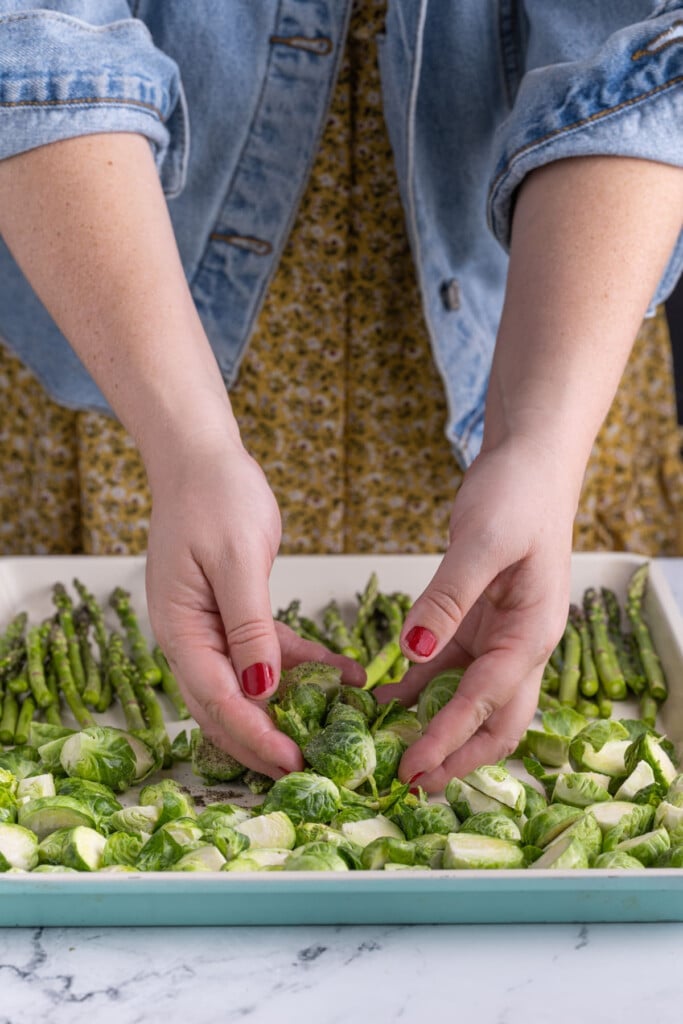 Tossing asparagus and brussels sprouts in olive oil and seasonings