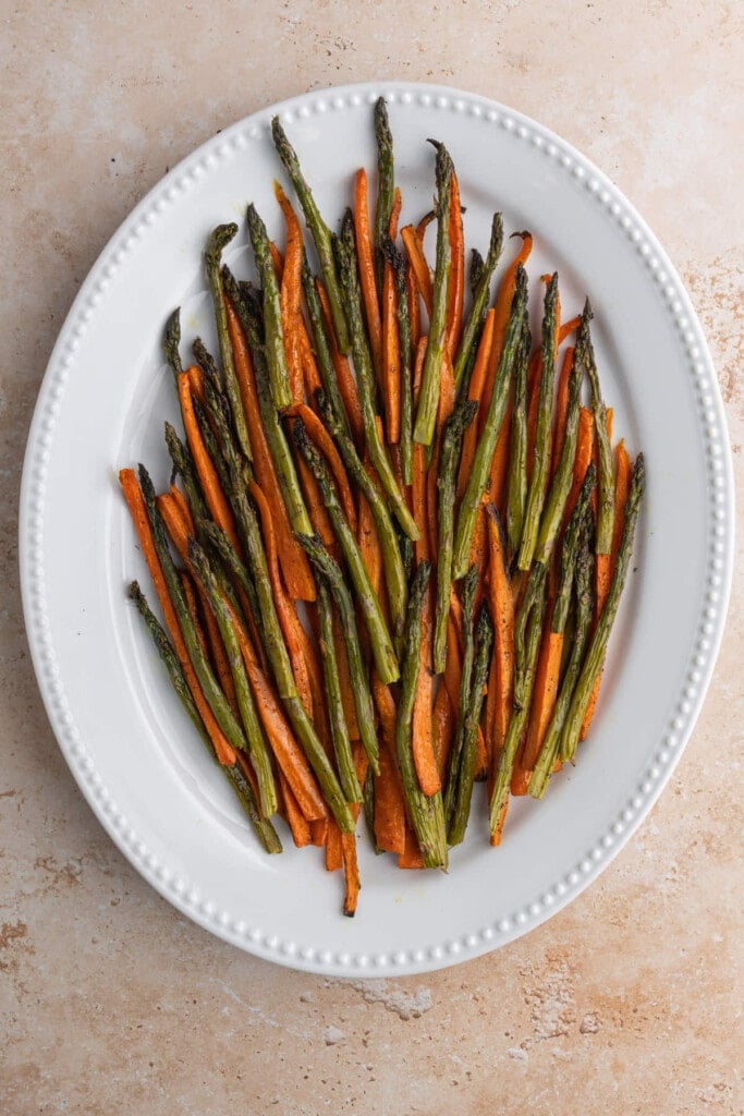 Roasted carrots and asparagus on a white serving platter