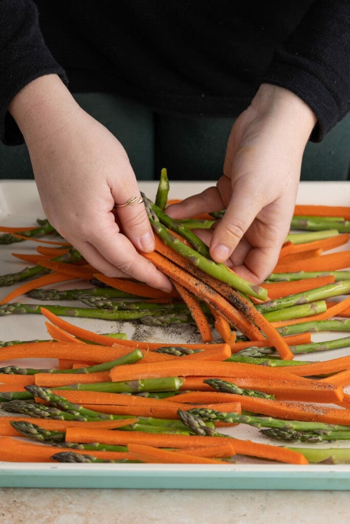 Tossing carrots and asparagus with olive oil, salt, and pepper