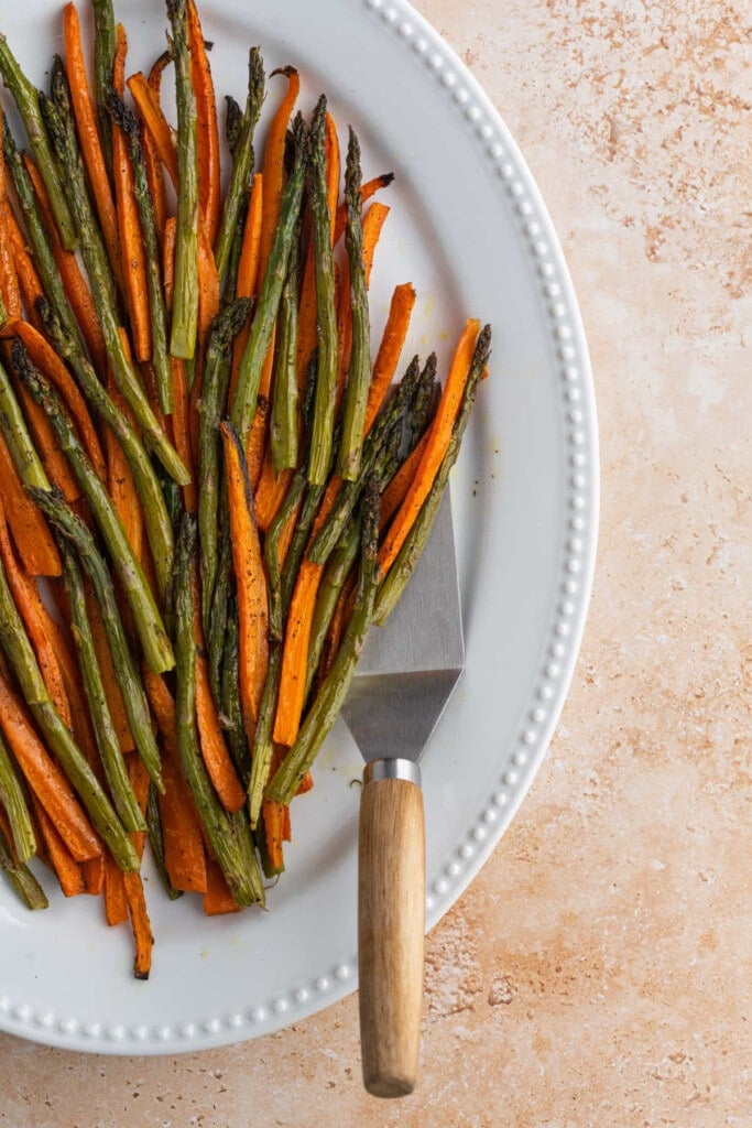 Plated roasted carrots and asparagus with serving utensil
