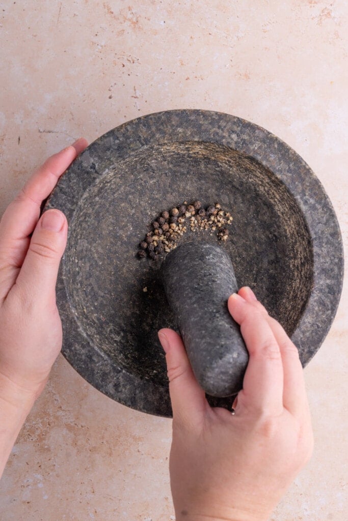 Crushing peppercorn with pestle and mortar