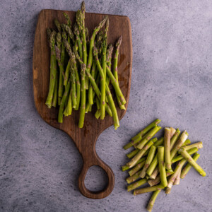 asparagus with the ends cut off on a wooden chopping board