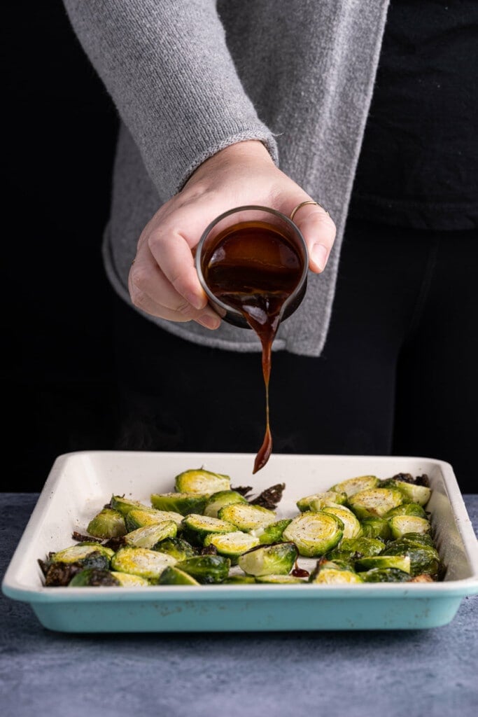 Pouring teriyaki sauce over brussels sprouts