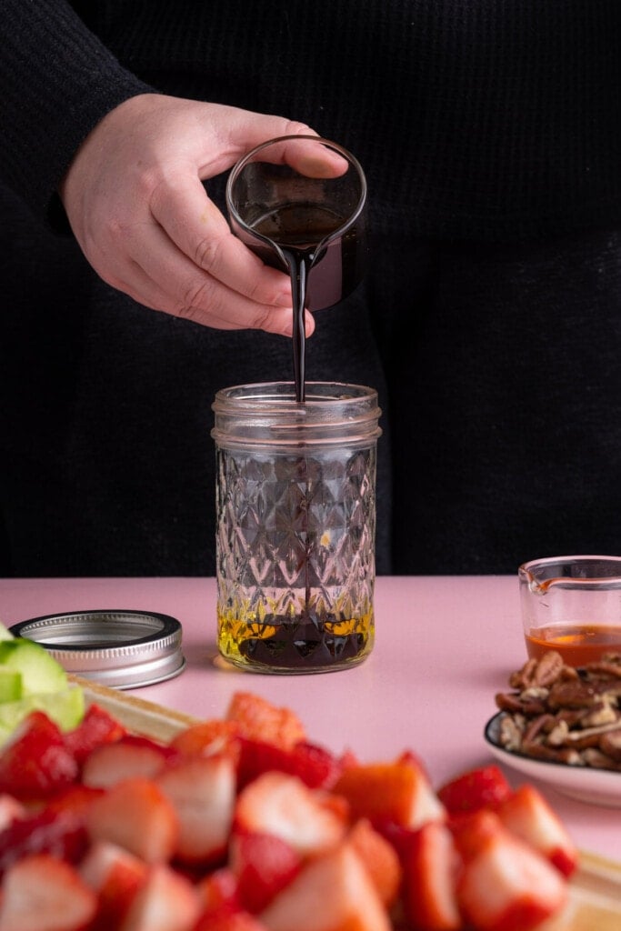 Mixing balsamic vinegar with olive oil and honey to make a simple vinaigrette
