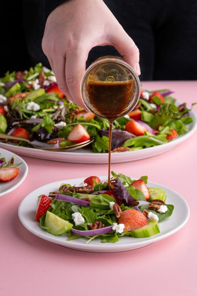 Pouring vinaigrette over salad when ready to serve
