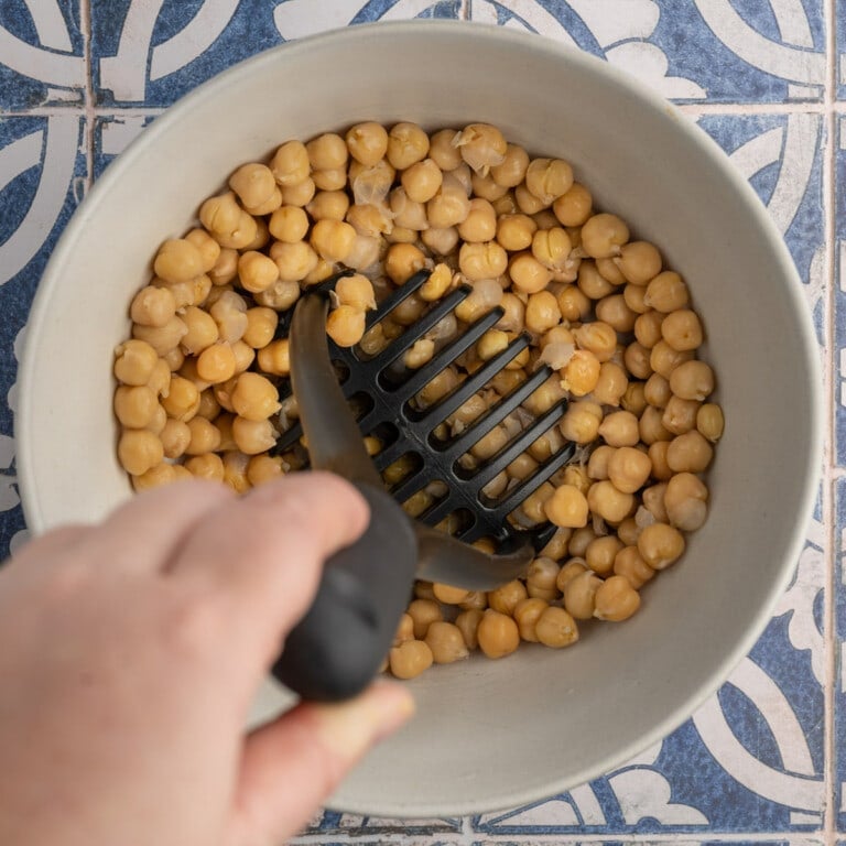 Smashing garbanzo beans with a potato masher